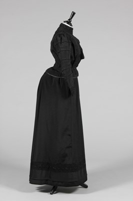 Lot 70 - A black faille mourning gown circa 1890,...