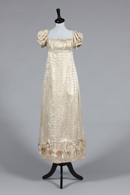 Lot 422 - An ivory figured silk gown circa 1815-20,...