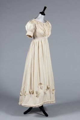 Lot 26 - An ivory figured silk dress, circa 1820, the...