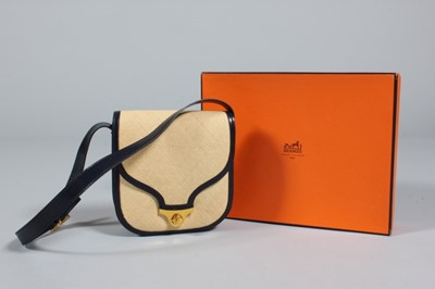 Lot 137 - An Hermès plaited straw and navy leather...