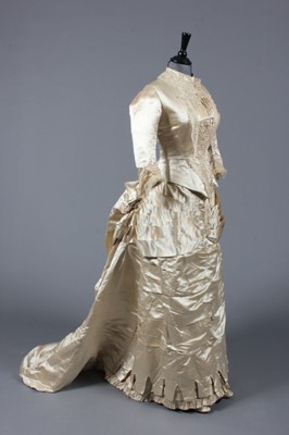 Lot 65 - An ivory satin bridal gown, c.1883-85, with...