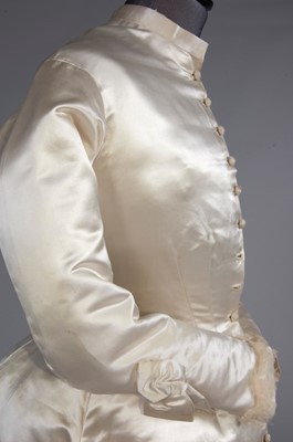 Lot 55 - An ivory satin bridal gown, late 1870s, of...