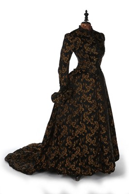 Lot 403 - A black and gold silk brocade gown, late 1880s,...