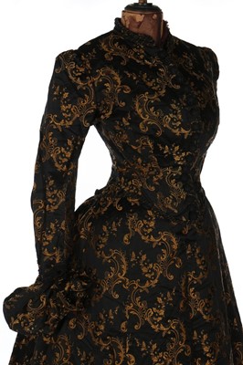 Lot 403 - A black and gold silk brocade gown, late 1880s,...