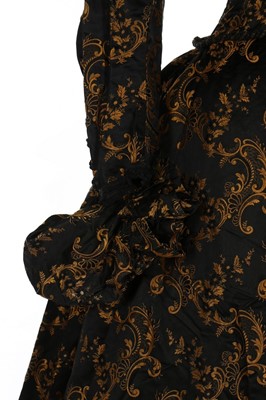 Lot 403 - A black and gold silk brocade gown, late 1880s,...