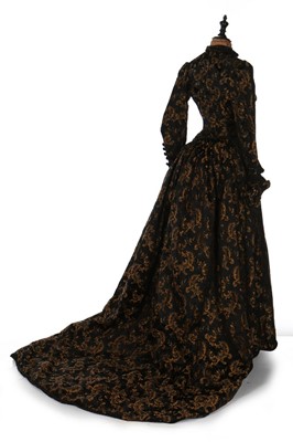 Lot 403 - A black and gold silk brocade gown, late 1880s,...