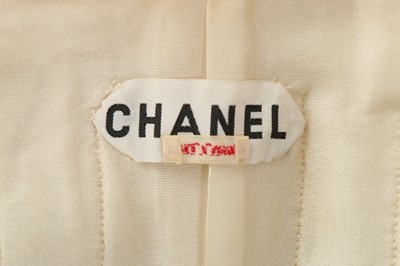 Lot 157 - A Chanel couture ivory tweed suit, 1964, broad...