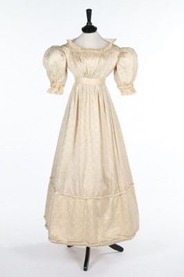 Lot 105 - An ivory figured silk gown, 1820s with later...