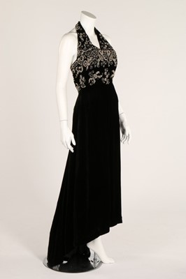 Lot 76 - A black velvet halter-neck evening dress,...