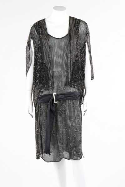 Lot 112 - A beaded black crepe flapper dress and similar...