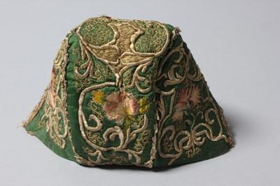 Lot 150 - An embroidered green satin baby cap, probably...